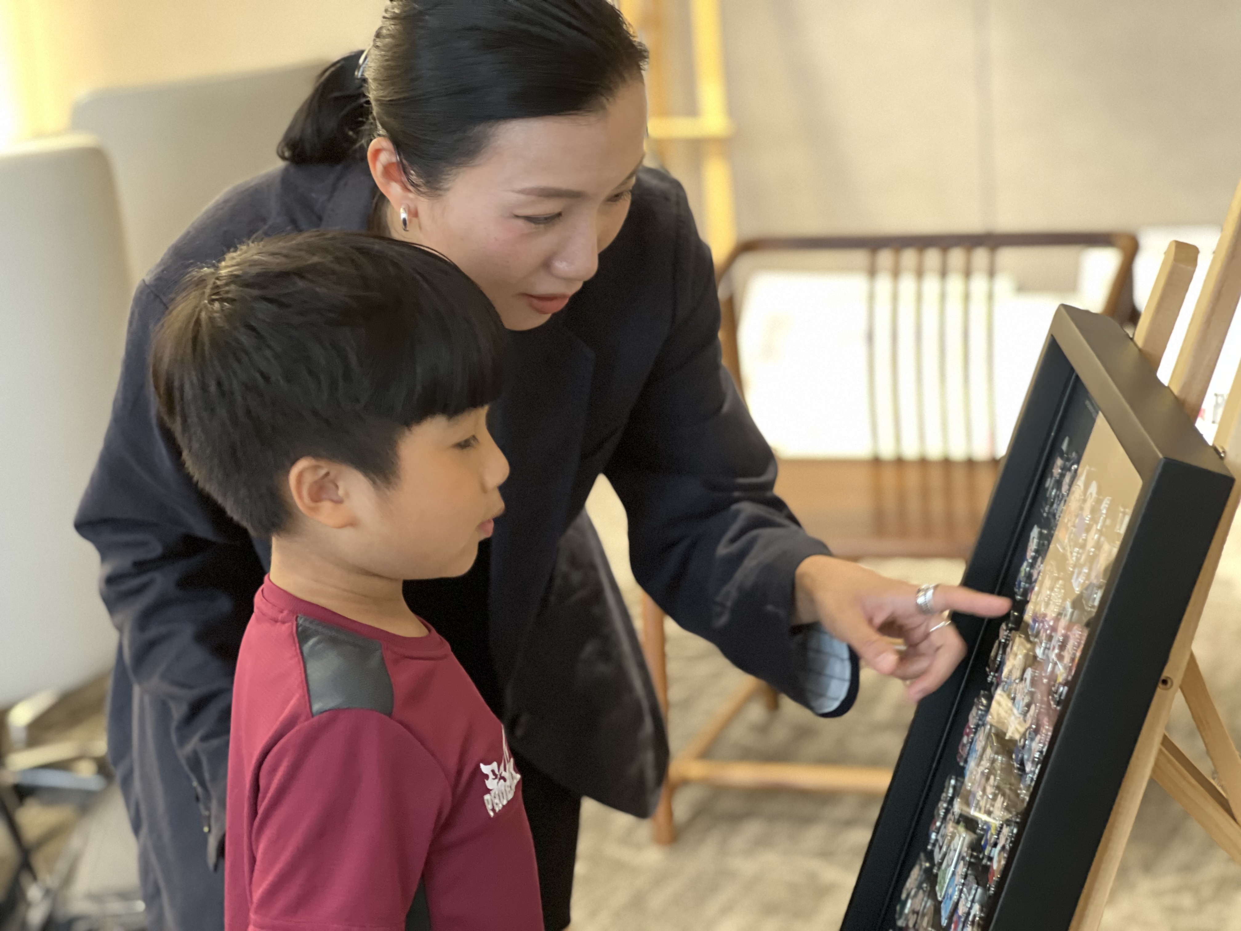 图说4:邓卓越在给儿子讲解民族娃娃®系列纪念徽章 (陈彦洁摄).jpg