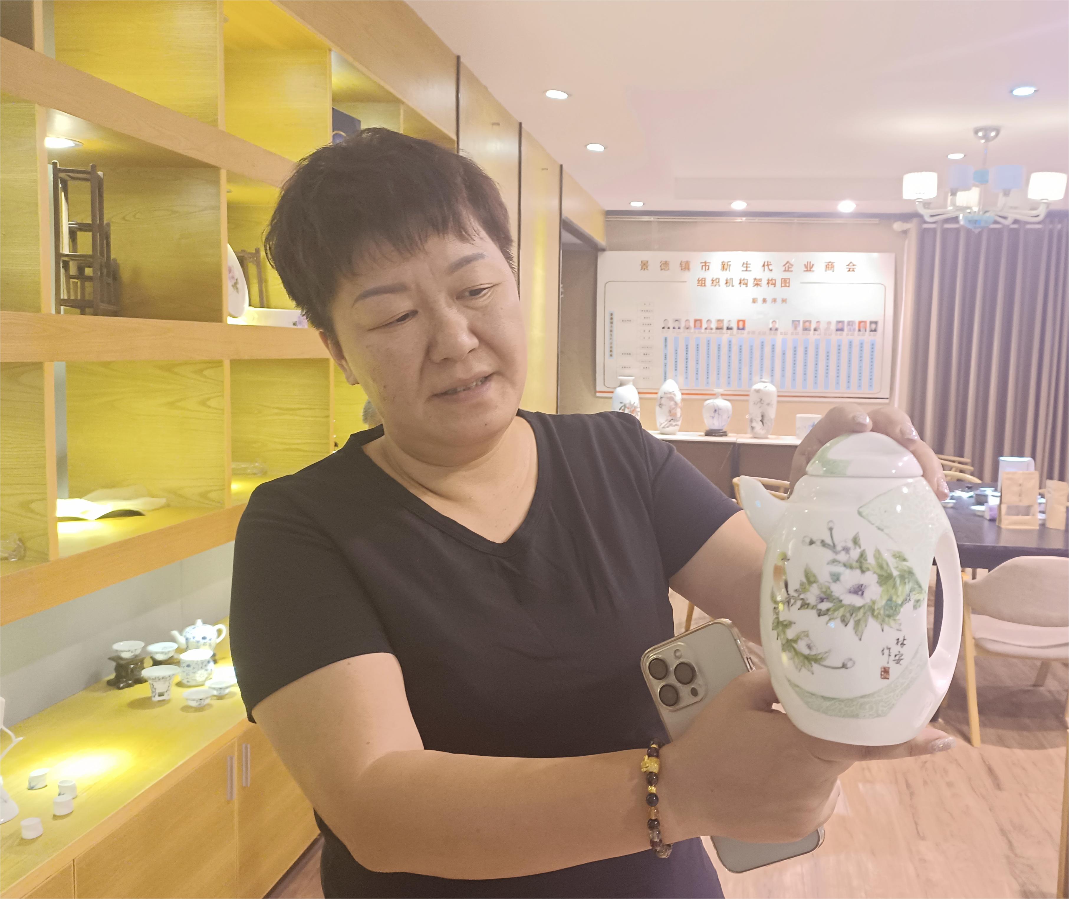 图一  黄红向记者展示手绘骨瓷“缘-企鹅”茶具.jpg